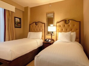 Ein Hotelzimmer mit zwei Betten, einem Nachttisch mit Lampe und einem Spiegel an der Wand.