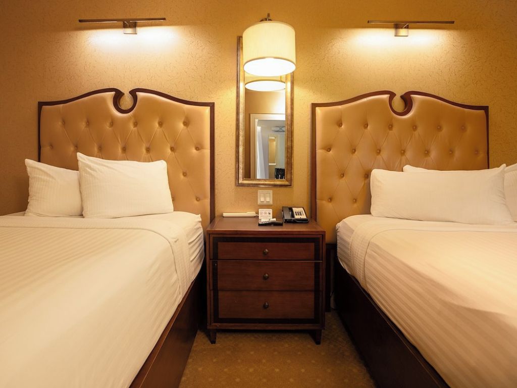 Ein Hotelzimmer mit zwei Betten, einem Nachttisch mit Telefon und einem Spiegel.