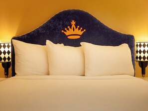 A bed with a dark headboard featuring a crown symbol, two bedside lamps with patterned bases, and a plain wall in the background. - King Room at King George Hotel | Near South of Market (SoMa) – 1.1 miles (San Francisco)