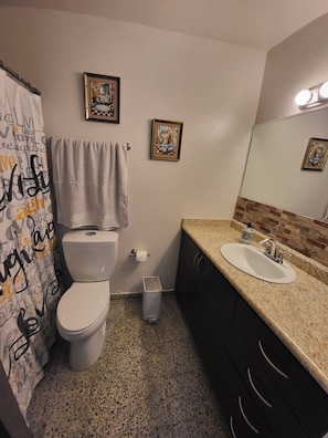 A bathroom with a toilet, sink, and two framed pictures on the wall.