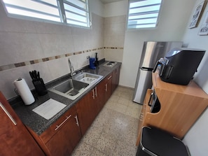 A compact kitchen with a sink, a coffee maker, and a refrigerator.