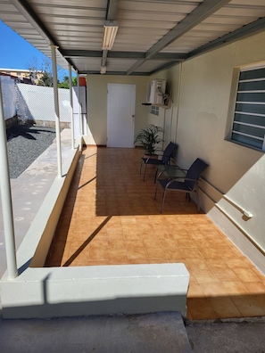 An outdoor patio with a tiled floor, a white door, and a potted plant.