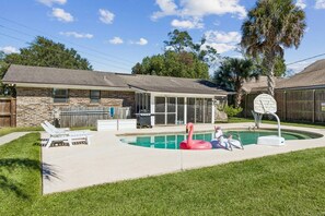 A backyard with a swimming pool, a covered patio, and a basketball hoop. - Aqua Oasis · Private Pool Bungalow, Fenced Yard (Jacksonville)