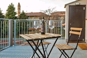 A balcony with a table, two chairs, and a bottle of wine. - Wine Loft in the Center of Monforte d'Alba (Monforte d'Alba)