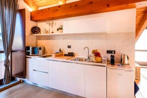 A modern kitchen with white cabinets, a built-in microwave, a sink, and a coffee maker. - Wine Loft in the Center of Monforte d'Alba (Monforte d'Alba)
