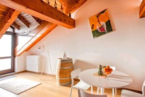A dining area with a round table, white chairs, a wooden barrel, and a cactus on the table. - Wine Loft in the Center of Monforte d'Alba (Monforte d'Alba)