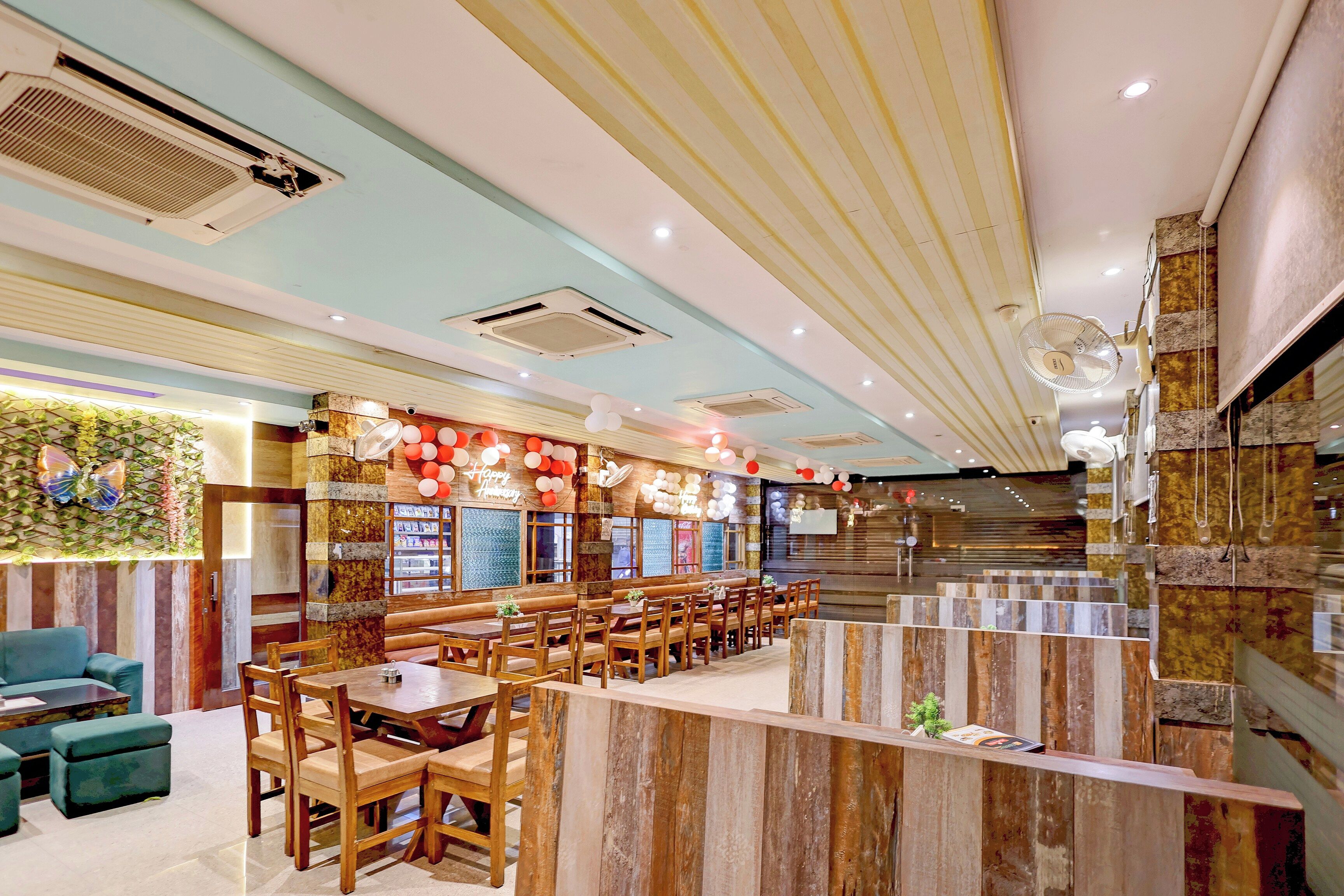 A restaurant interior with wooden furniture, a bar area, and decorative balloons.
