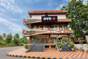 A hotel with a checkered floor pattern, a staircase leading to the entrance, and multiple signs indicating the hotel name and amenities. - Hotel O Essence Inn (Prayagraj)