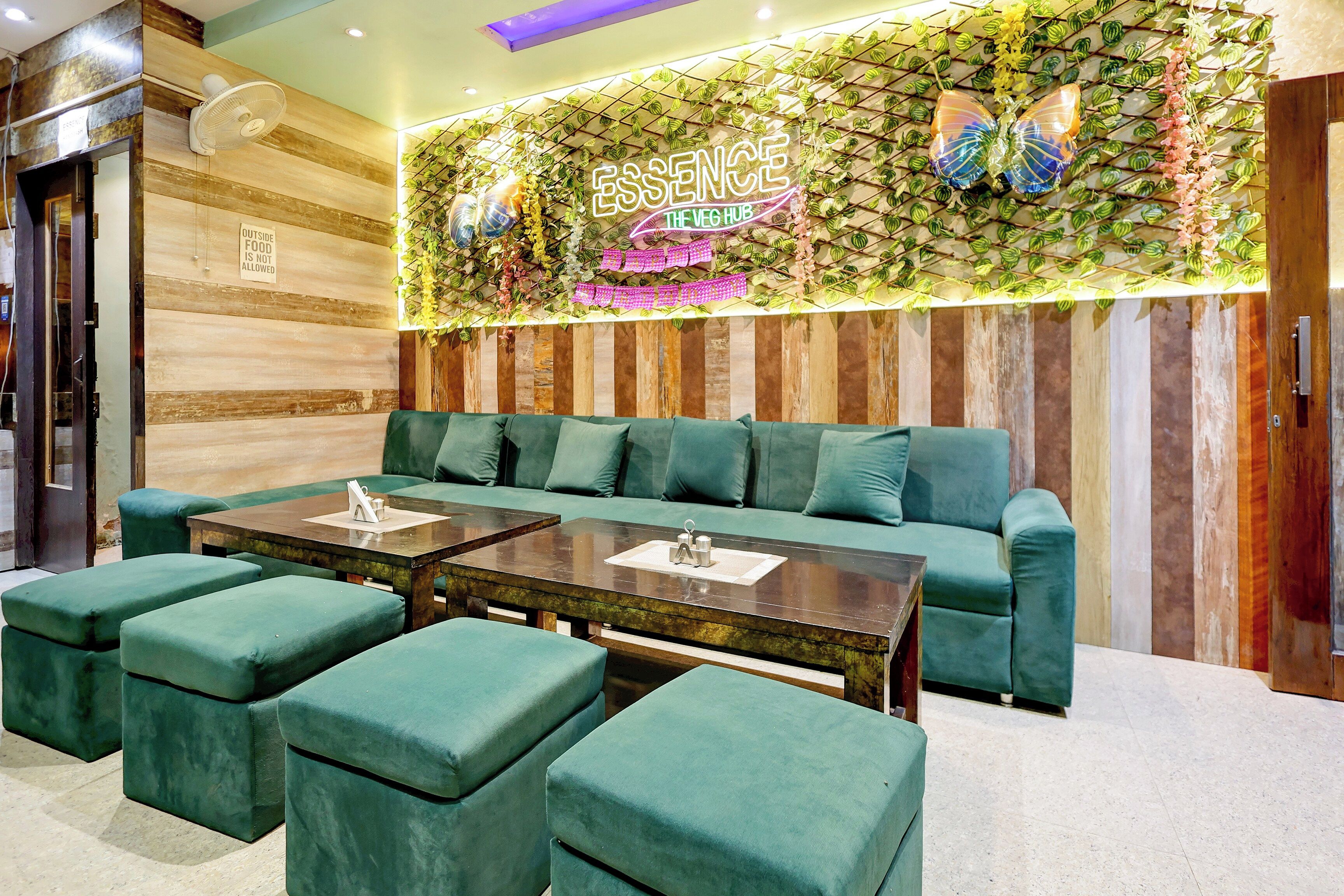 A modern lounge area with a green sofa, two matching tables, and matching ottomans.