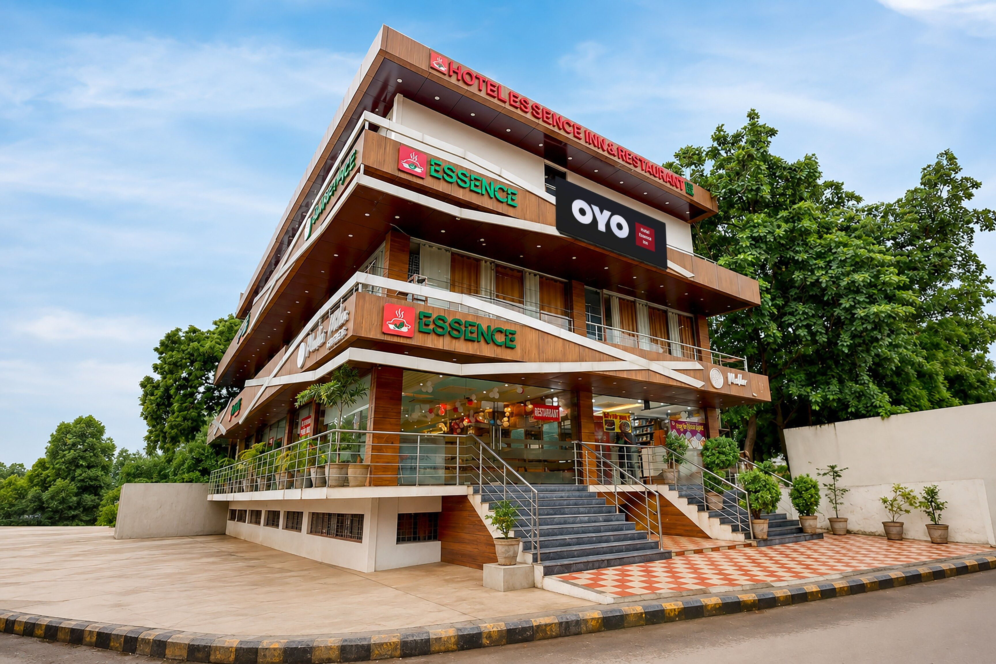 A multi-story hotel with a prominent 'ESSENCE' sign, a 'YO' sign, and a restaurant sign.