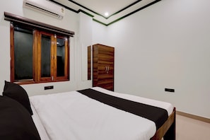A bedroom with a bed, a wardrobe, and a window. - Hotel O Essence Inn (Prayagraj)
