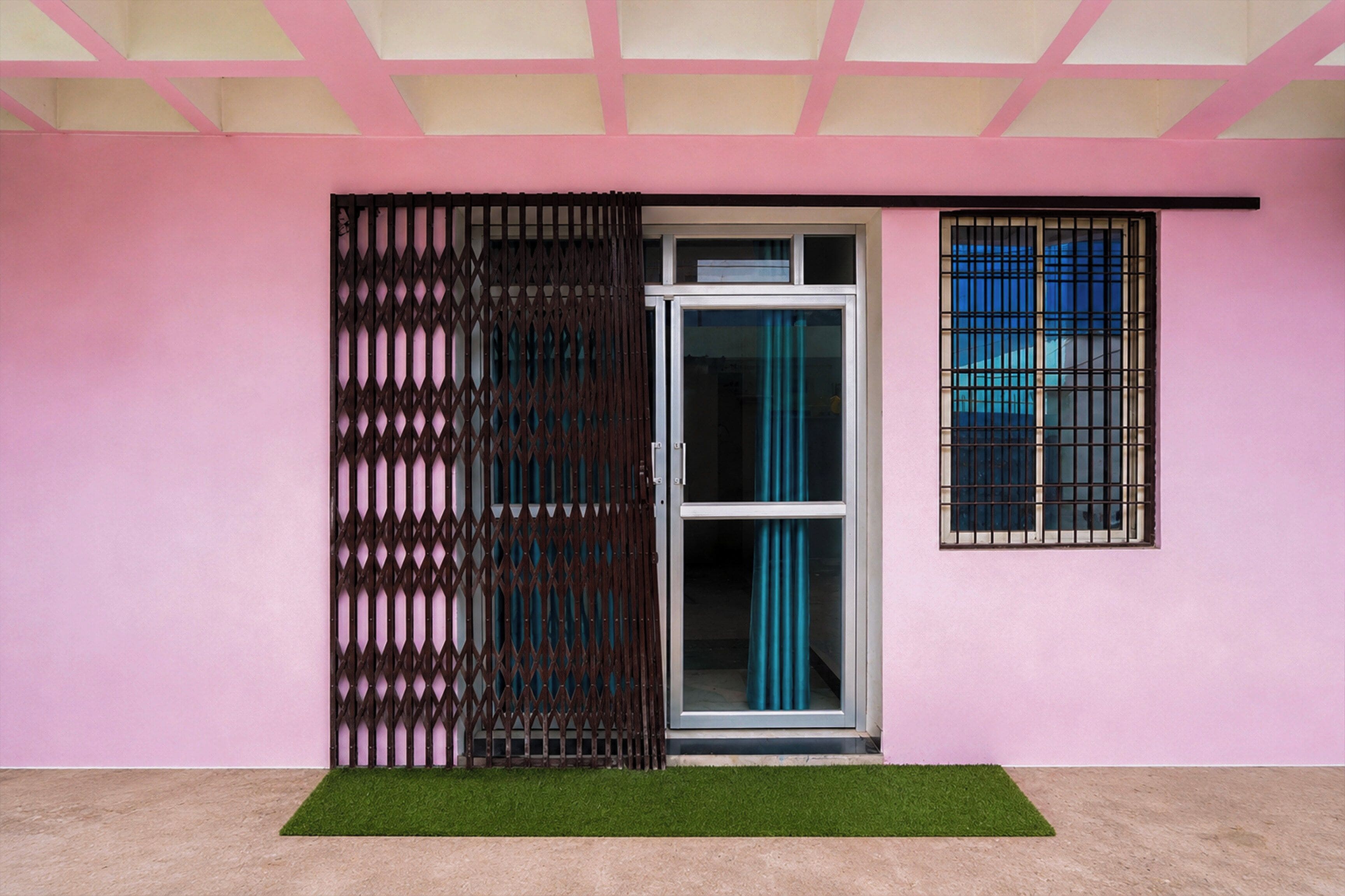 Pared cor de rosa com porta deslizante e janela com grades de metal.