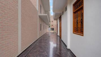 A corridor with brick walls, a polished floor, and a wooden door with a window.