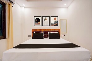 A hotel room with a large bed, a headboard with a wooden panel, and three framed artworks on the wall. - Hotel O Awadh Stay Inn (Soraon)