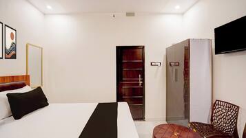 A hotel room with a bed, a chair, a TV, and a wardrobe.