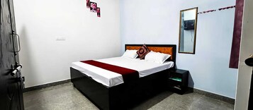 Un dormitorio con cama, mesita de noche, espejo y puerta.
