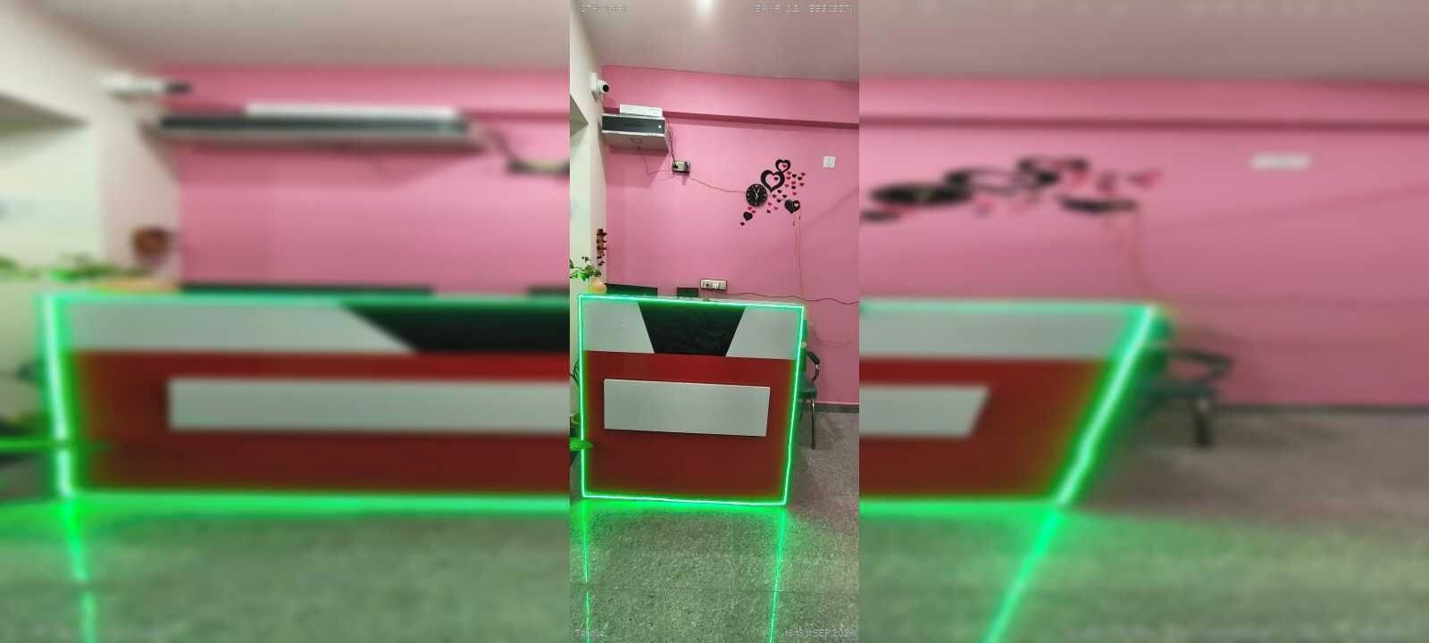 Un mostrador de recepción con una pared rosa y una esquina iluminada en verde.