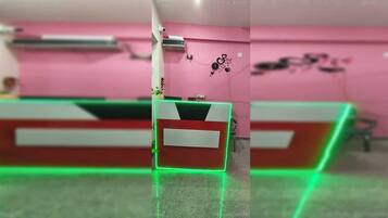 Un mostrador de recepción con una pared rosa y una esquina iluminada en verde.