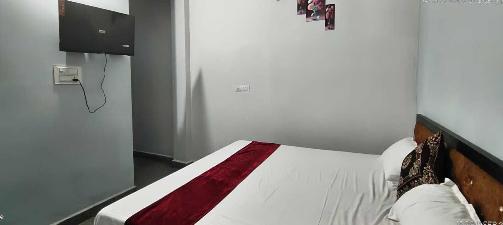 Une chambre d’hôtel équipée d’un lit, d’un téléviseur à écran plat fixé au mur et d’une prise de courant au mur.