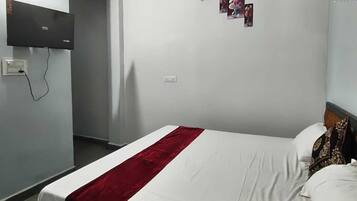 Une chambre d’hôtel équipée d’un lit, d’un téléviseur à écran plat fixé au mur et d’une prise de courant au mur.