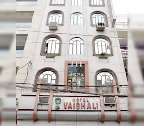 Un edificio con un letrero que dice 'HOTEL VAISHALI' y varias ventanas.