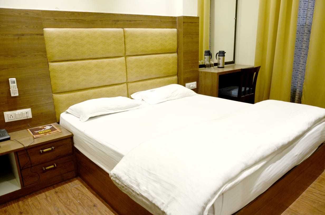 A hotel room with a large bed, a wooden nightstand with a phone, and a small table with a coffee maker.