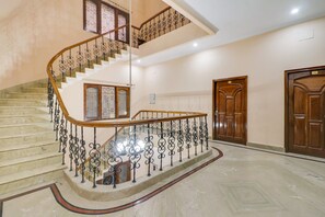 A multi-level interior with a marble staircase, a wooden door, and a wall-mounted light fixture. - Hotel O Raka Inn (Prayagraj)
