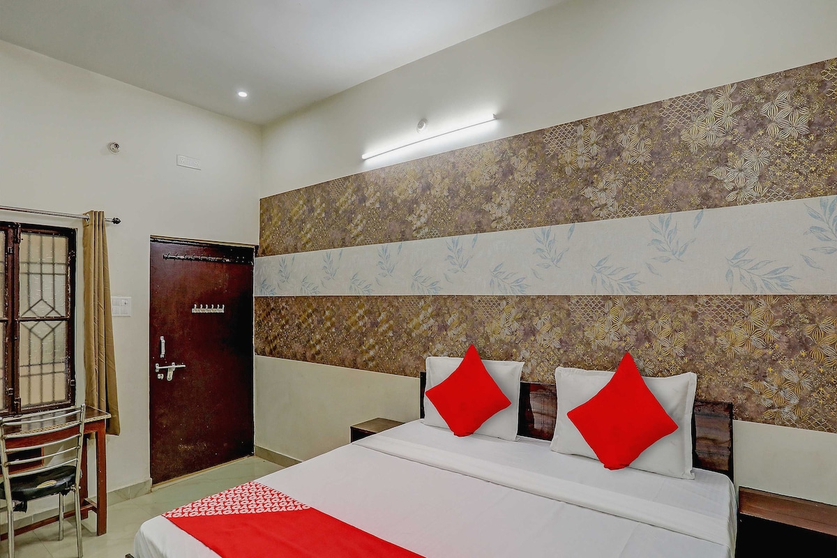 A hotel room with a bed, a wooden door, a chair, and a patterned wall.