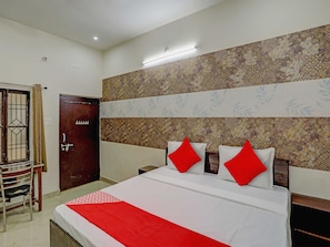 A hotel room with a bed, a wooden door, a chair, and a patterned wall. - Hotel O The Raghav Villa (Prayagraj)