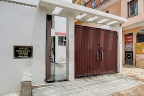 A gated entrance with a metal door, a signboard, and a small step leading to the entrance. - Hotel O The Raghav Villa (Prayagraj)