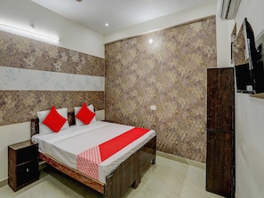 A bedroom with a bed, a nightstand, a wardrobe, and patterned wallpaper. - Hotel O The Raghav Villa (Prayagraj)