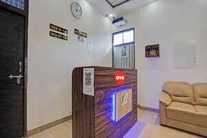 A reception desk with a wooden finish and a QR code, a clock on the wall, and a sign indicating check-in and check-out times.