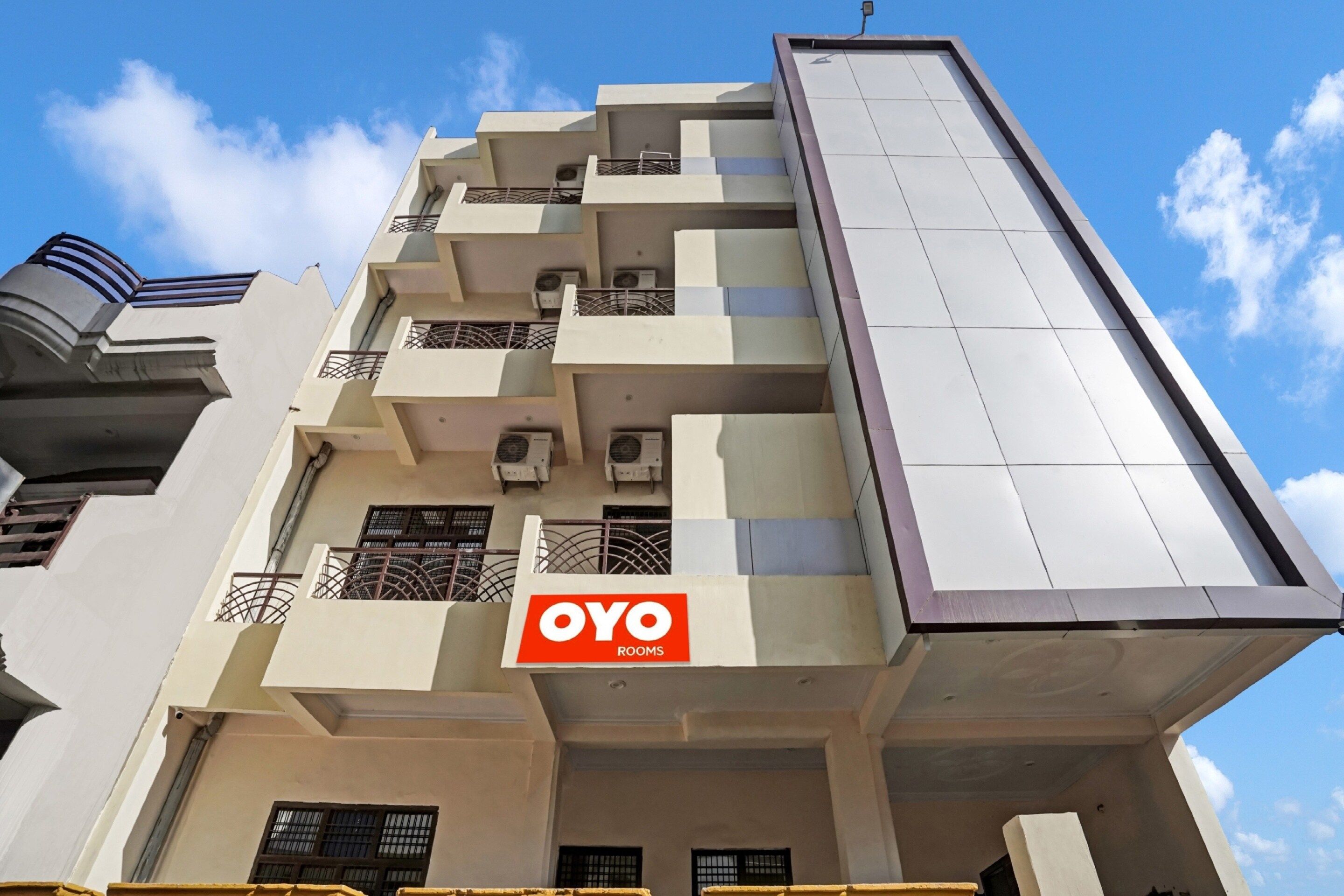 A multi-story building with a prominent 'OYO ROOMS' sign, air conditioning units, and a modern architectural design.