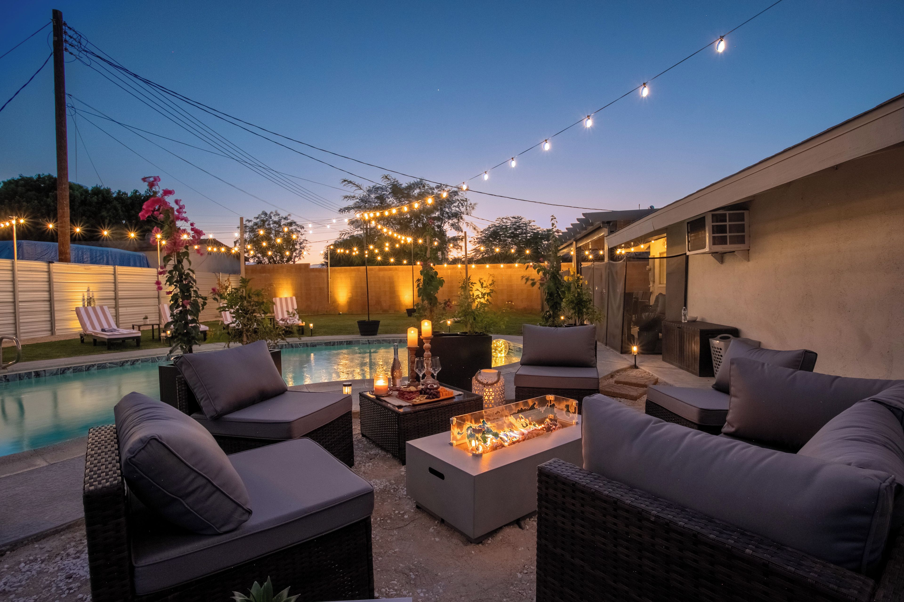 An outdoor patio area with a pool, lounge chairs, and string lights.