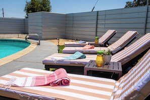 A poolside area with lounge chairs, a small table with a plant, and a pool. - The Velvet Cactus, Private Pool, Fire Pit, BBQ, & King Bed (Indio)