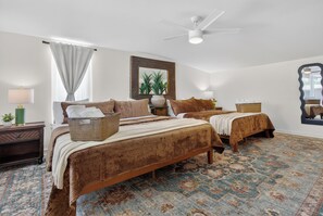 Une chambre avec deux lits, un ventilateur de plafond, un grand miroir et un tapis à motifs.