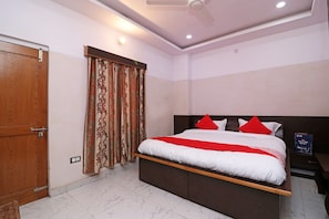 Une chambre à coucher avec un lit, des rideaux, un ventilateur de plafond et une table de chevet.