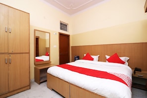 A hotel room with a bed, a wardrobe, a mirror, a bedside table, and a nightstand.