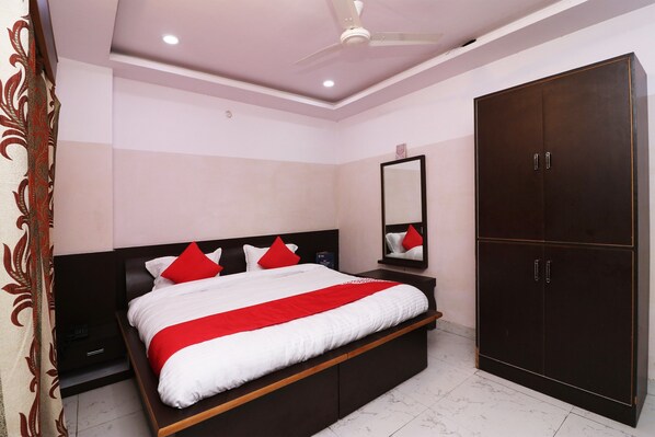 A bedroom with a bed, nightstands, a wardrobe, a ceiling fan, and a mirror.