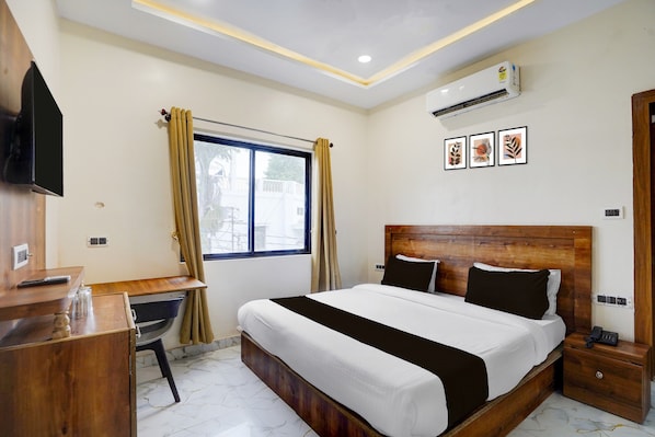 A hotel room with a bed, a desk, a chair, a TV, and an air conditioning unit. - Hotel O Hotel Madhvam (Prayagraj)