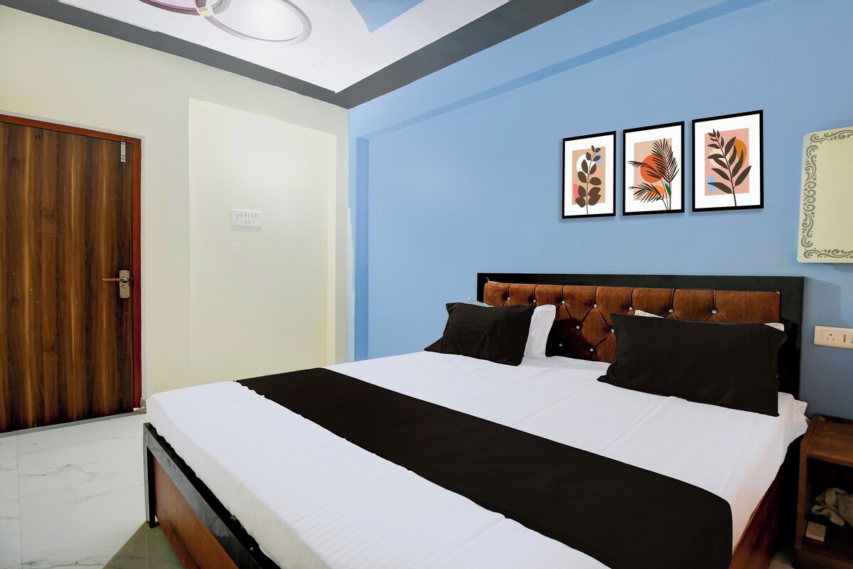 A bedroom with a bed, a wooden door, and three framed pictures on the wall.