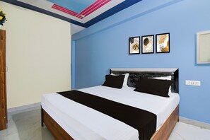A bedroom with a bed, a nightstand, a wall-mounted power outlet, and a ceiling with a decorative light fixture. - Hotel O Rahul Inn (Prayagraj)