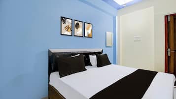 Une chambre à coucher comprenant un lit, une tête de lit, un luminaire fixé au mur et trois œuvres d’art encadrées.