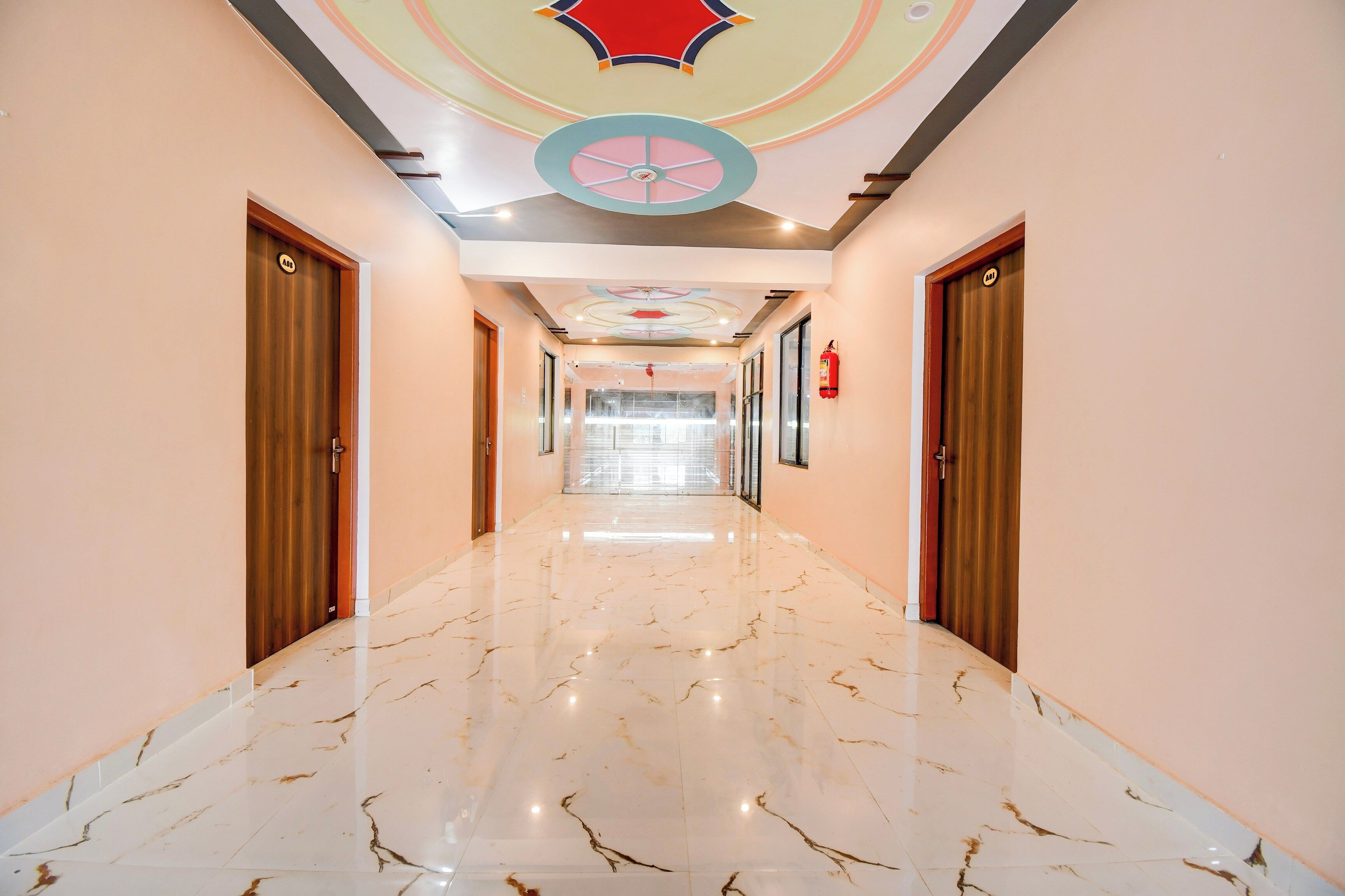 Un pasillo de hotel con suelo de mármol, puertas de madera y un techo decorativo.