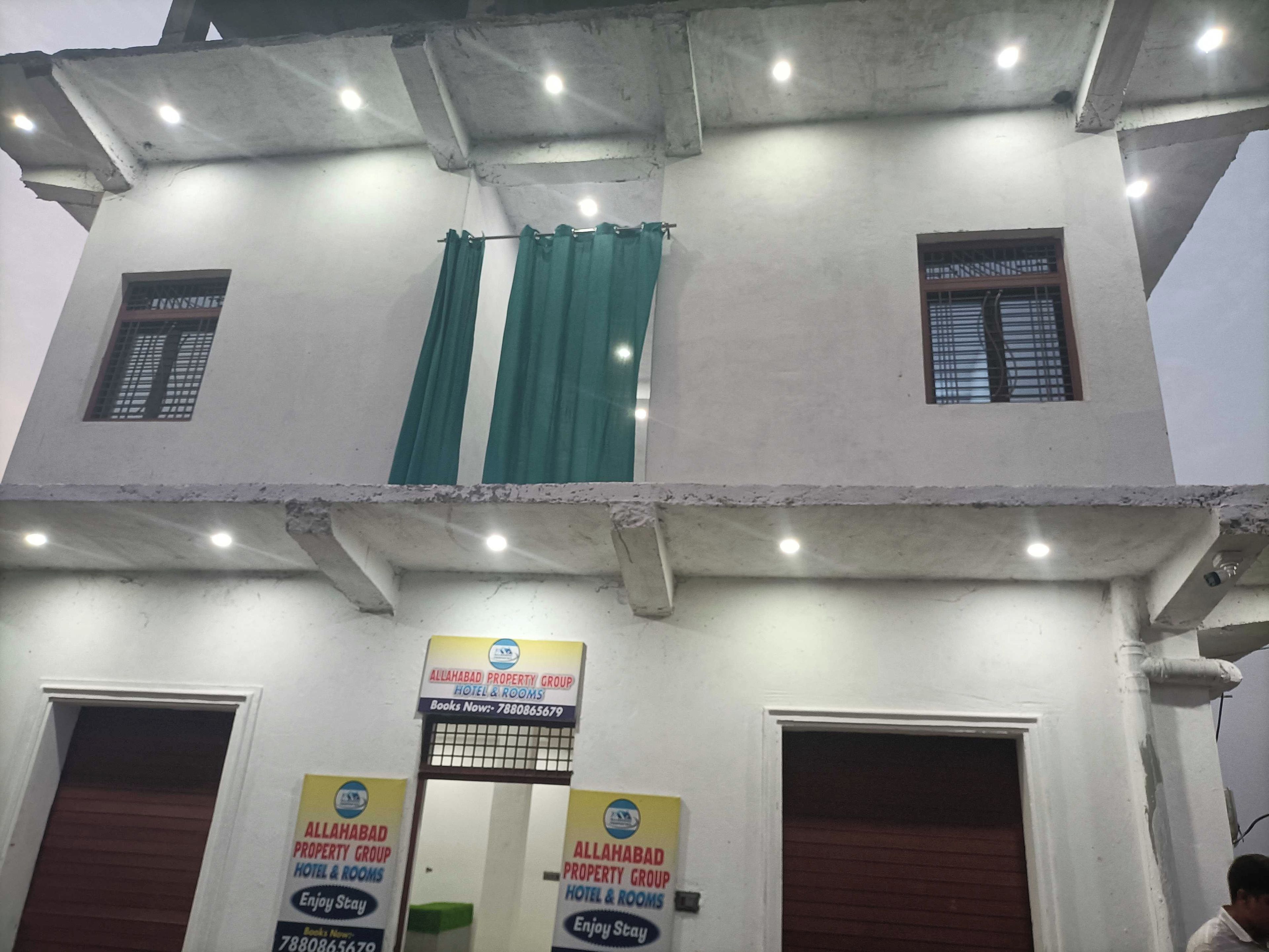 A two-story building with a sign for Allahabad Property Group Hotel & Rooms.