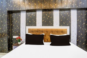 Een hotelkamer met een bed, een nachtkastje en een bloemenvaas.