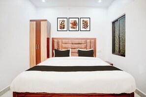 Een slaapkamer met een bed, een kledingkast en drie ingelijste kunstwerken aan de muur.