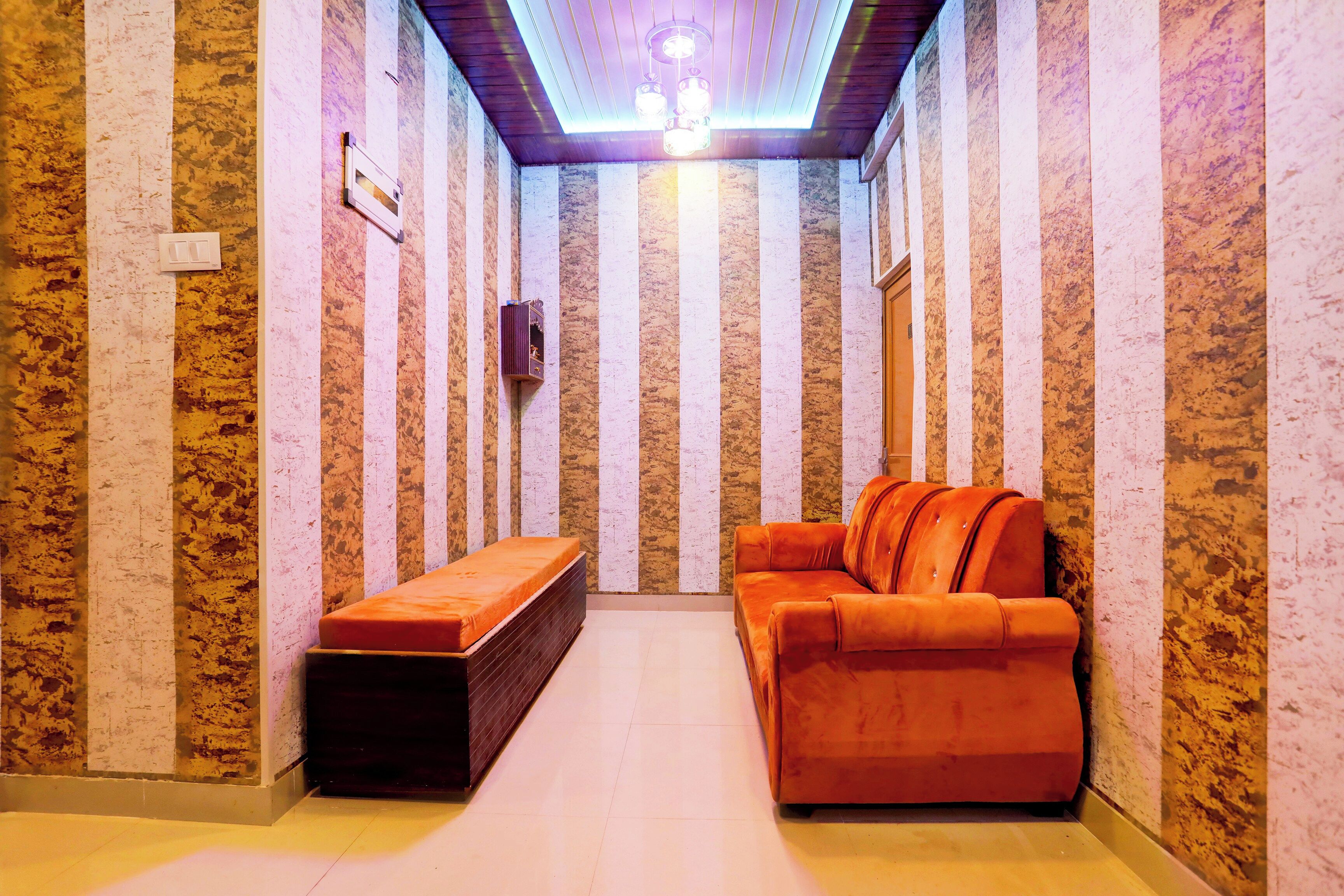 A narrow hallway with a bench and a sofa, a ceiling light, and a wall-mounted TV.