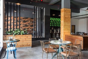 Et moderne caféinteriør med runde borde, metalstole og en væg med trædetaljer.