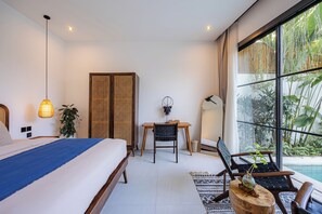 A modern bedroom with a large bed, a desk, and a view of a lush garden through a large window. - 2BR Private Pool Villa with Rice Field Views & Sunset Balconies (Badung)